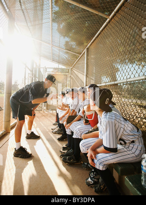 USA, California, Ladera Ranch, Boys (10-11) from little league sitting on dugout while coach talking Stock Photo