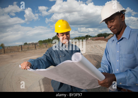 Two construction workers discussing blueprints on building site Stock Photo