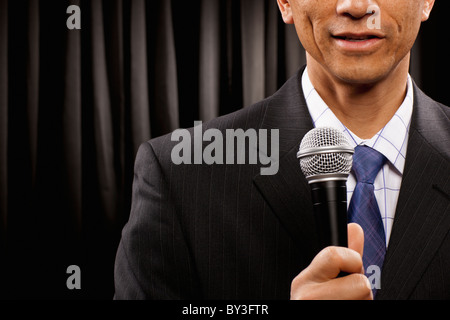 USA, Utah, Provo, Close-up of businessman with microphone standing in front of black curtain, mid section Stock Photo