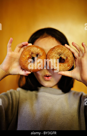 Girl holding donuts over eyes. Stock Photo
