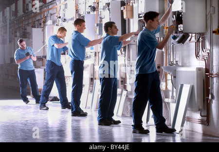Learning on the job Apprentice gas fitters fit boilers in plumbing class Stock Photo