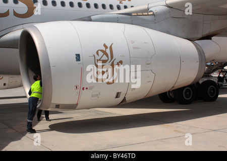 Airport employee inspecting a Rolls-Royce Trent 700 jet engine on the wing of an Emirates Airbus A330-200 plane Stock Photo