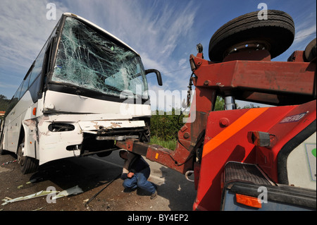 Man attaching a wrecked bus with shattered windscreen glass after a car crash to a tow truck Stock Photo