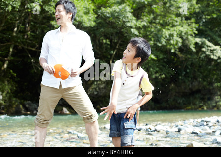 Father and Son Playing in River Stock Photo