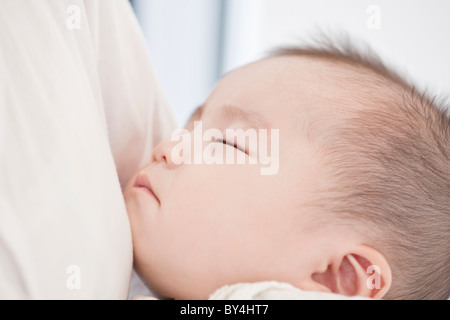 Baby boy sleeping in mother's arm Stock Photo