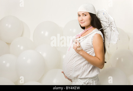 Portrait of elegant pregnant woman in fashionable clothes holding decorative umbrella Stock Photo