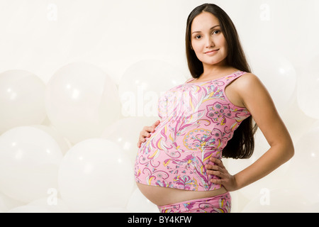 Portrait of pregnant woman wearing colorful tanktop on background of balloons Stock Photo