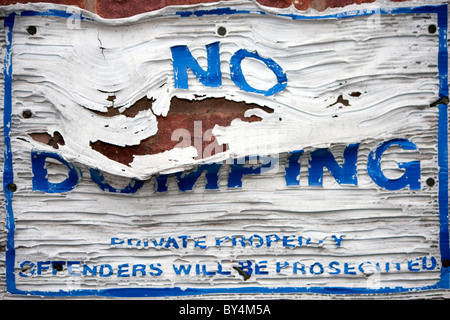 a no dumping sign that has been set on fire and melted during an act of vandalism Stock Photo