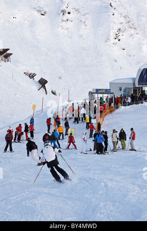 Skiers and snowboarders joining a queue to get on the Arlenmahder chairlift in the Austrian ski resort of St Anton. Stock Photo