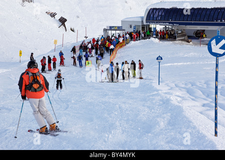 Skiers and snowboarders joining a queue to get on the Arlenmahder chairlift in the Austrian ski resort of St Anton. Stock Photo