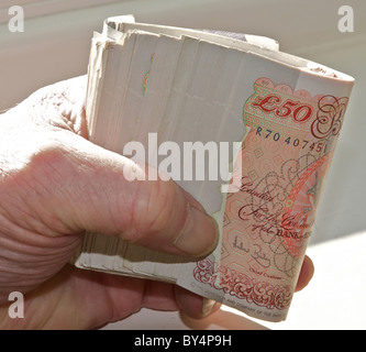 Sterling currency, a roll of UK bank notes thousand pounds in hand. (Fully released - photographer's own hand). From the archives of Press Portrait Service (formerly Press Portrait Bureau) Stock Photo