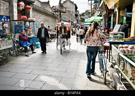 CHINA, XI'AN: Busy street scene in the old Muslim quarter of Xian, China, with food vendors and pedicabs along with shoppers. Stock Photo