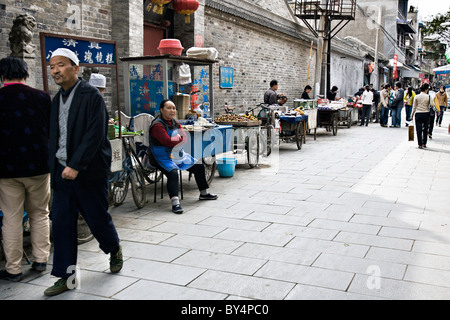 CHINA, XIAN: Chinese vendors selling vegetables and food along a pedestrian walkway in the old Muslim Quarter of Xian. Stock Photo