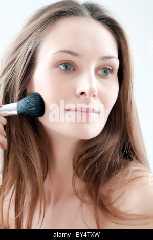 young woman applying blush on cheek Stock Photo