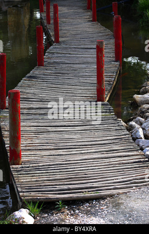 A wooden rickety bridge over a large pond or small lake full of water Stock Photo