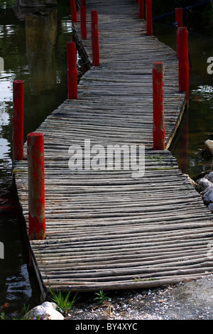 A wooden rickety bridge over a large pond or small lake full of water Stock Photo