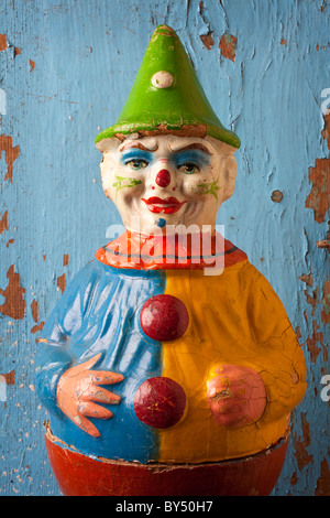 Old clown toy close up against worn blue wall Stock Photo