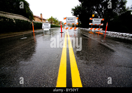 Three stop signs warn traffic away from a washed out road following heavy rain in Southern California. Stock Photo