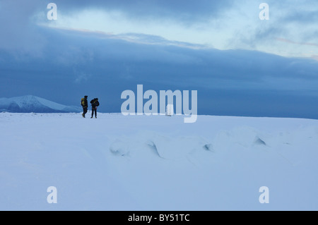 Walkers on the summit of Helvellyn at dusk in winter in the English Lake District Stock Photo