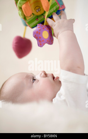 A baby reaching up to touch a mobile Stock Photo
