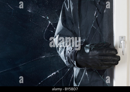 A criminal breaking into a window, focus on hand Stock Photo