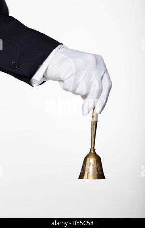 A butler ringing a hand bell for service, focus on hand Stock Photo