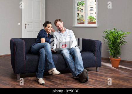 A young couple using a laptop together in their living room Stock Photo