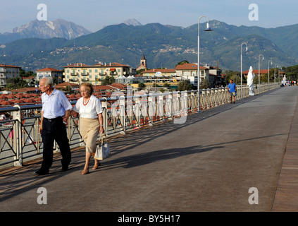 An old couple stroll along the pier at Marina di Pietrasanta near Forte dei Marmi , Versilia Riviera in Tuscany , Italy Stock Photo