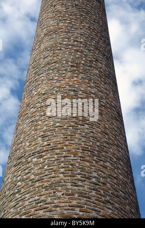 Weathered brick chimney of an old factory. Industrial architecture. Stock Photo