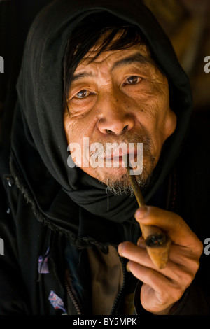 Old Jinuo man smoking pipe, Jinuo Luoke (Jinuo Shan), Jinghong, Xishuangbanna, Yunnan Province, China. JMH4321 Stock Photo