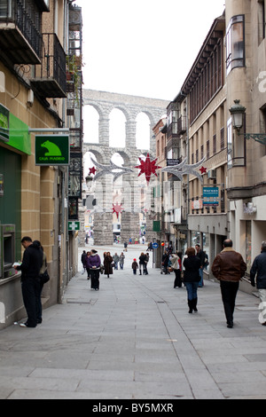 People walking down the street during winter in Segovia, Spain. Roman Aqueduct of Segovia in the background. Stock Photo