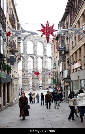 People walking down the street during winter in Segovia, Spain. Roman Aqueduct of Segovia in the background. Stock Photo