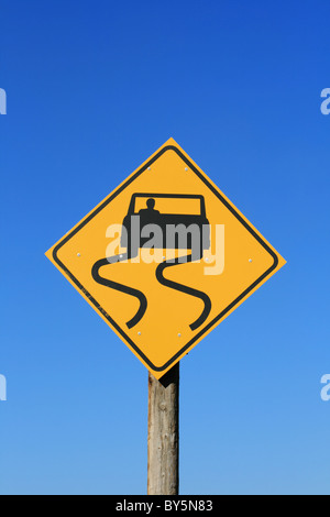 slippery road sign with car and skid marks in black on yellow with blue sky background Stock Photo