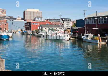 Commercial charter and lobster fishing boats line the waterway between two piers in Portland, Maine Stock Photo