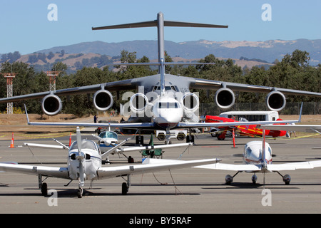 United States Air Force C-17 Globemaster III sits on the ramp with a variety of general aviation aircraft . Stock Photo