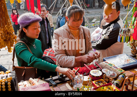 Beautiful young Chinese girl in green top and purple cap shopping in Huanglongxi, near Chengdu, Sichuan Province, China. JMH4354 Stock Photo