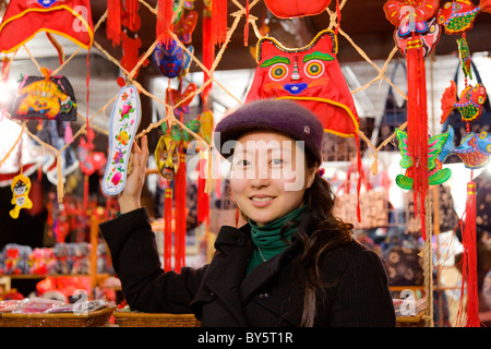 Beautiful young Chinese girl wearing purple fluffy cap shopping in Huanglongxi, near Chengdu, Sichuan Province, China. JMH4362 Stock Photo