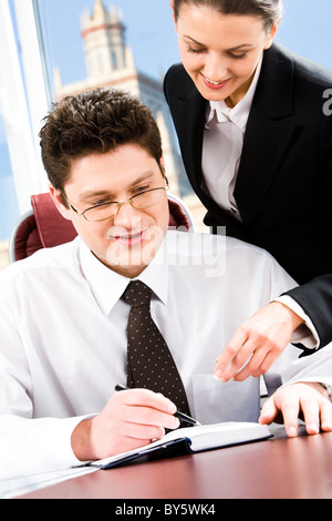 Portrait of two business people in the office pointing at something in the notebook Stock Photo