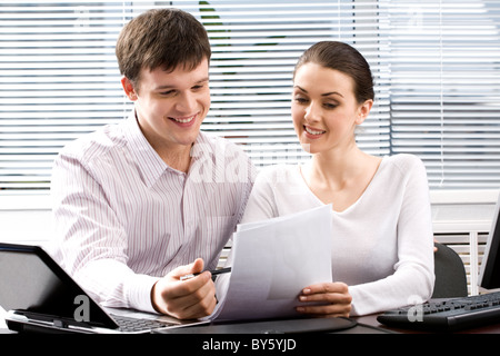 Image of two confident people reading a document together in the office Stock Photo
