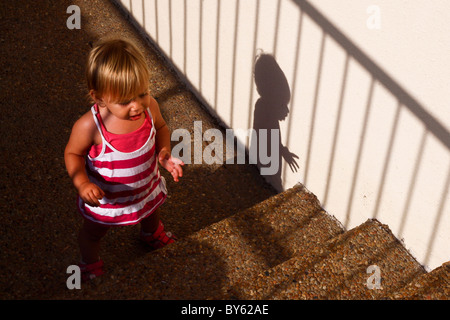 Young girl of two attempting to climb stairs Stock Photo