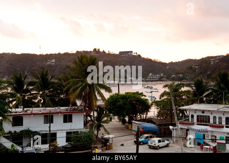 beautiful rose pink sunset afterglow over bay hills sky & town of Puerto Angel Oaxaca State Mexico Stock Photo