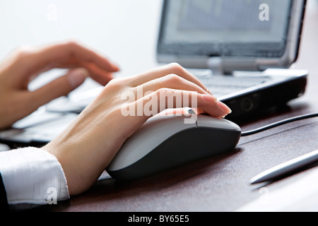 Human hands touching computer mouse and keys of opened laptop Stock Photo