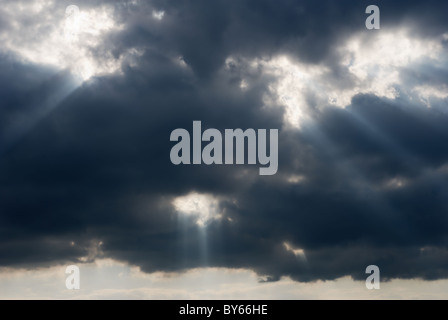 Bright sunbeams bursting through dark clouds Stock Photo