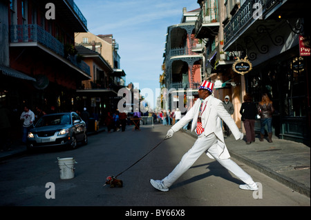 A man pretends to walk across the street behind a stuffed dog on a street in New Orleans, Louisiana. Stock Photo