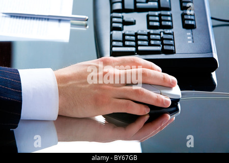 Photo of male hand using computer mouse lying on a workplace Stock Photo