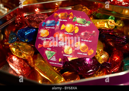 tin and explanation sheet of wrapped up quality street chocolate sweets in colourful wrappers Stock Photo