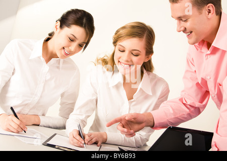 Image of young man pointing at paper in which pretty female going to write something Stock Photo