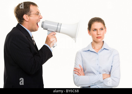 Portrait of angry boss shouting at his secretary through megaphone who is indifferent to it Stock Photo