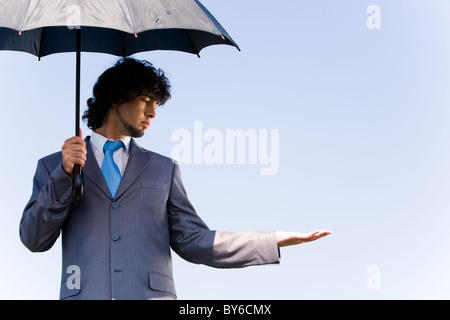 Portrait of confident businessman waiting a rain under the umbrella Stock Photo