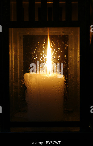 candle in glass holder with rain drops at night Stock Photo